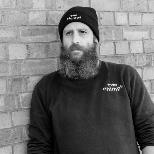 leaning against a wall wearing a two chimps coffee beanie hat