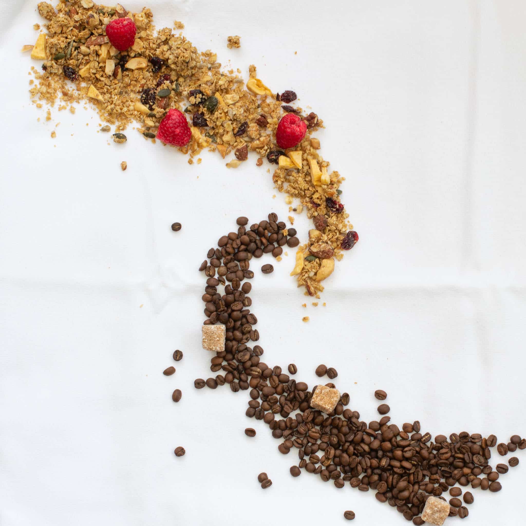 Swirl of granola and raspberries and swirl of coffee beans and sugar cubes 