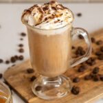 Caramel coffee on a wooden board surrounded by coffee beans