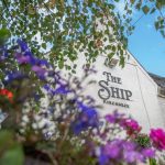 Close up of The Ship pub seen through flowers