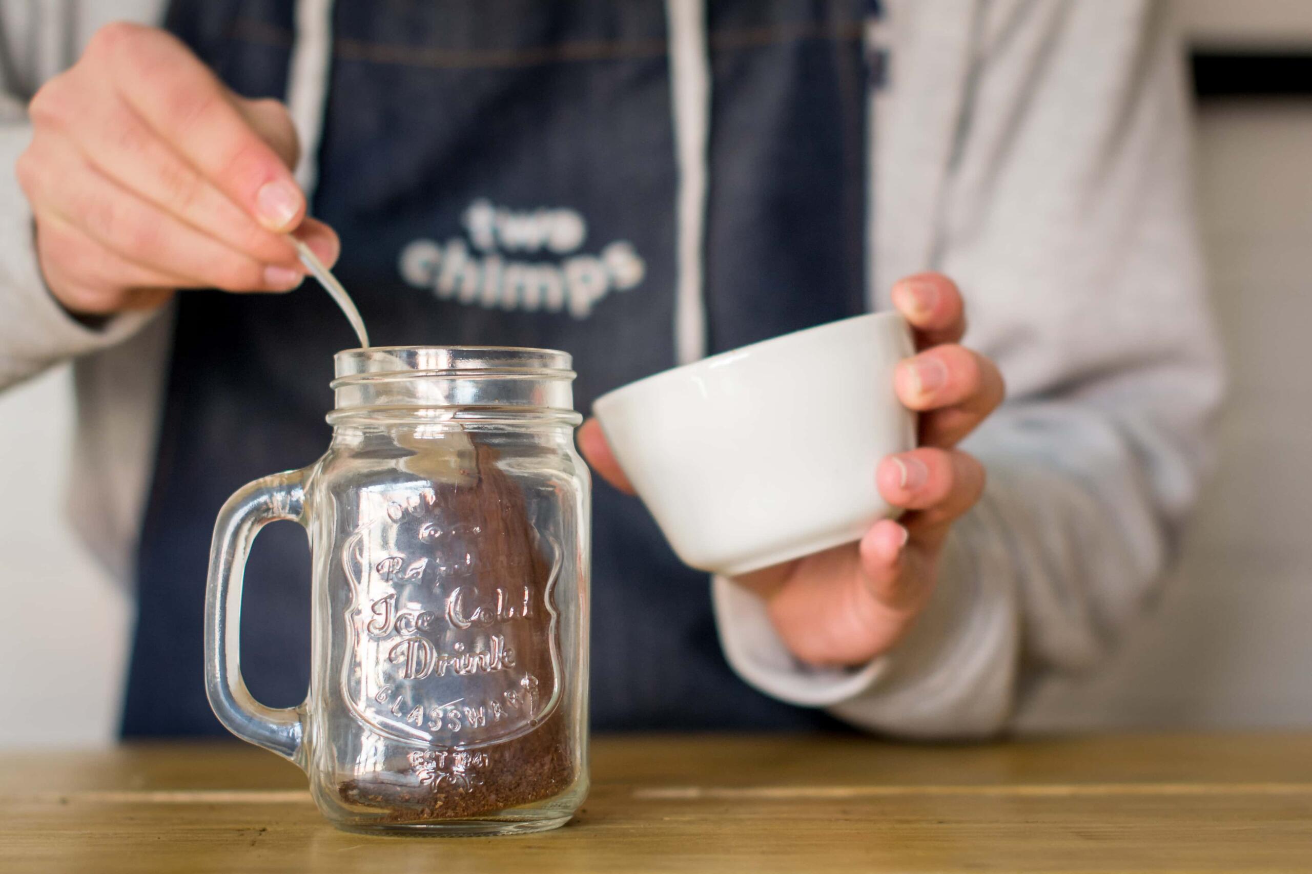 Adding coffee grounds to mason jar