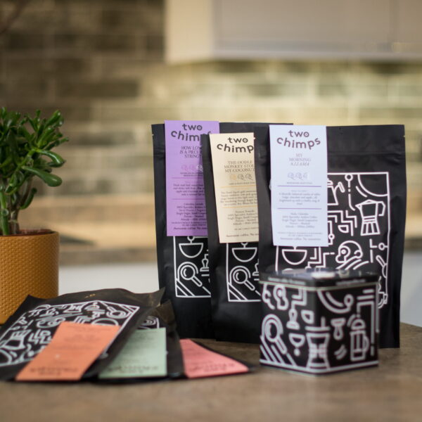 6 bags of coffee on kitchen worktop with two chimps coffee tin and magnet