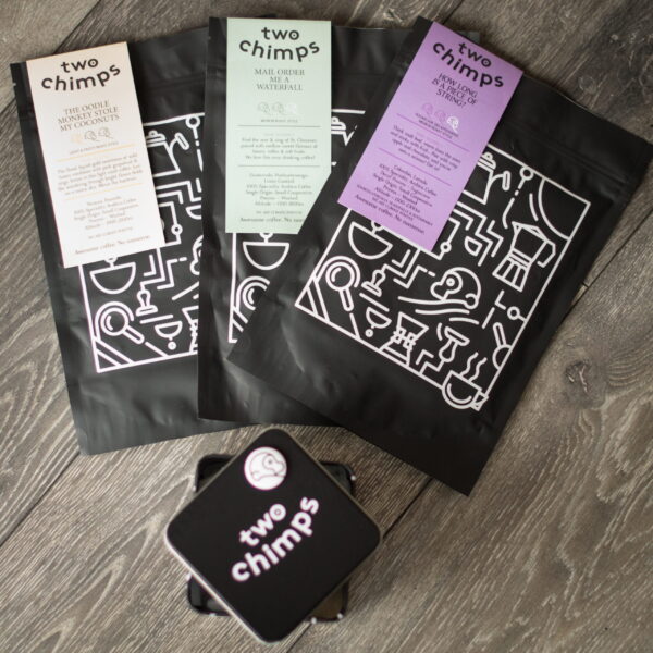 bird eye view of three coffee bags and two chimps tin and magnet