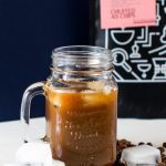 non dairy iced coffee in glass sitting in front of Two Chimps cafetiere coffee