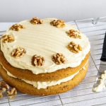 Coffee and walnut cake on wire rack with spatula and walnuts