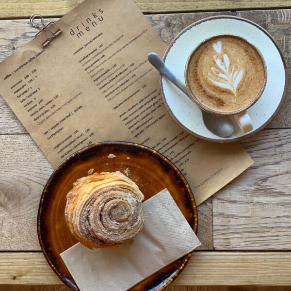 A tasty pastry and a flat white with a beautiful latte art tulip at The Larder Burrough Court