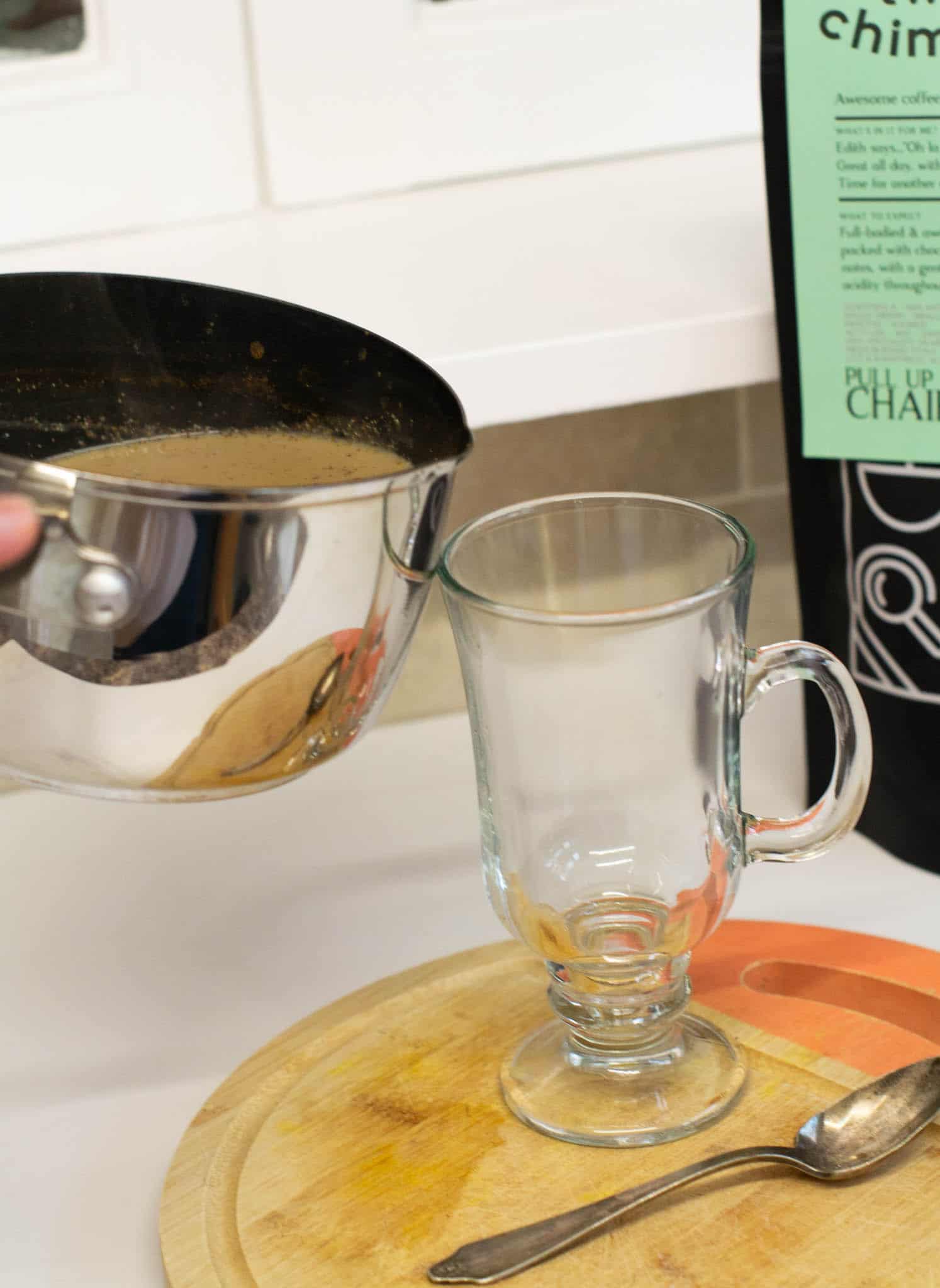 Pouring pumpkin latte from saucepan into latte glass