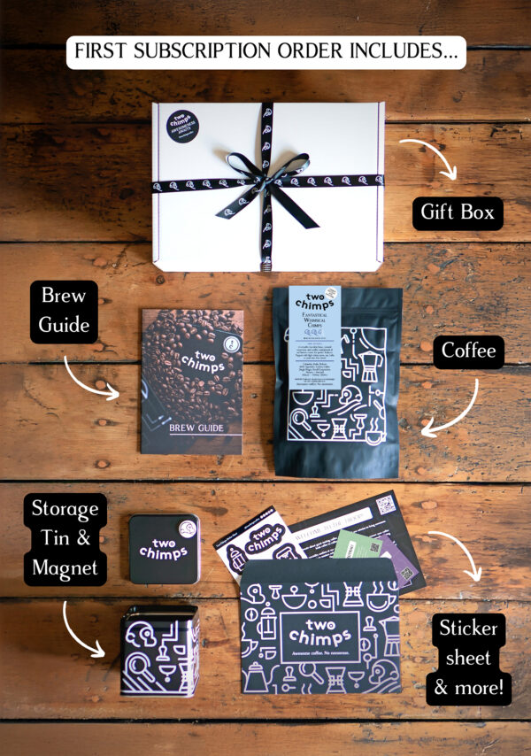 An image of a Two Chimps Coffee subscription box with the items included in it such as the brew guide, the storage tin & magnet and the coffee bag