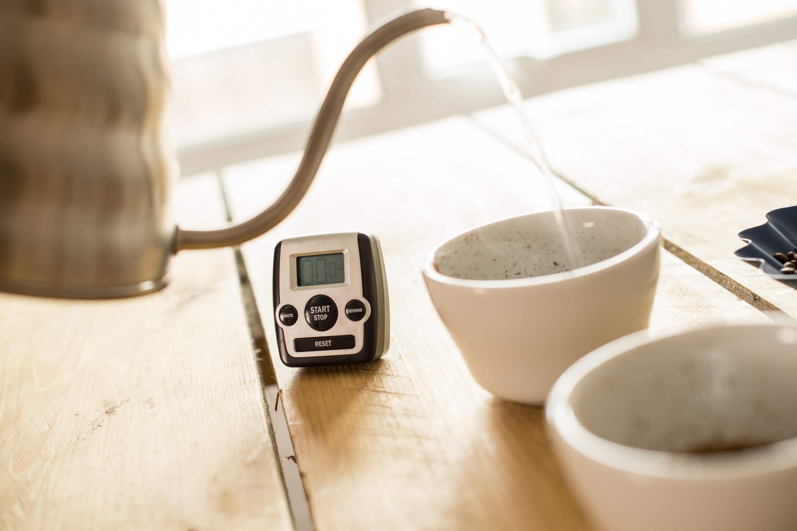 Pouring water into a cupping bowl of coffee with a timer set