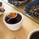 Someone putting a spoon in coffee