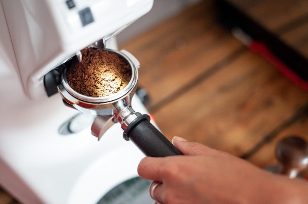 fresh coffee grounds tipping from a grinder into a portafilter