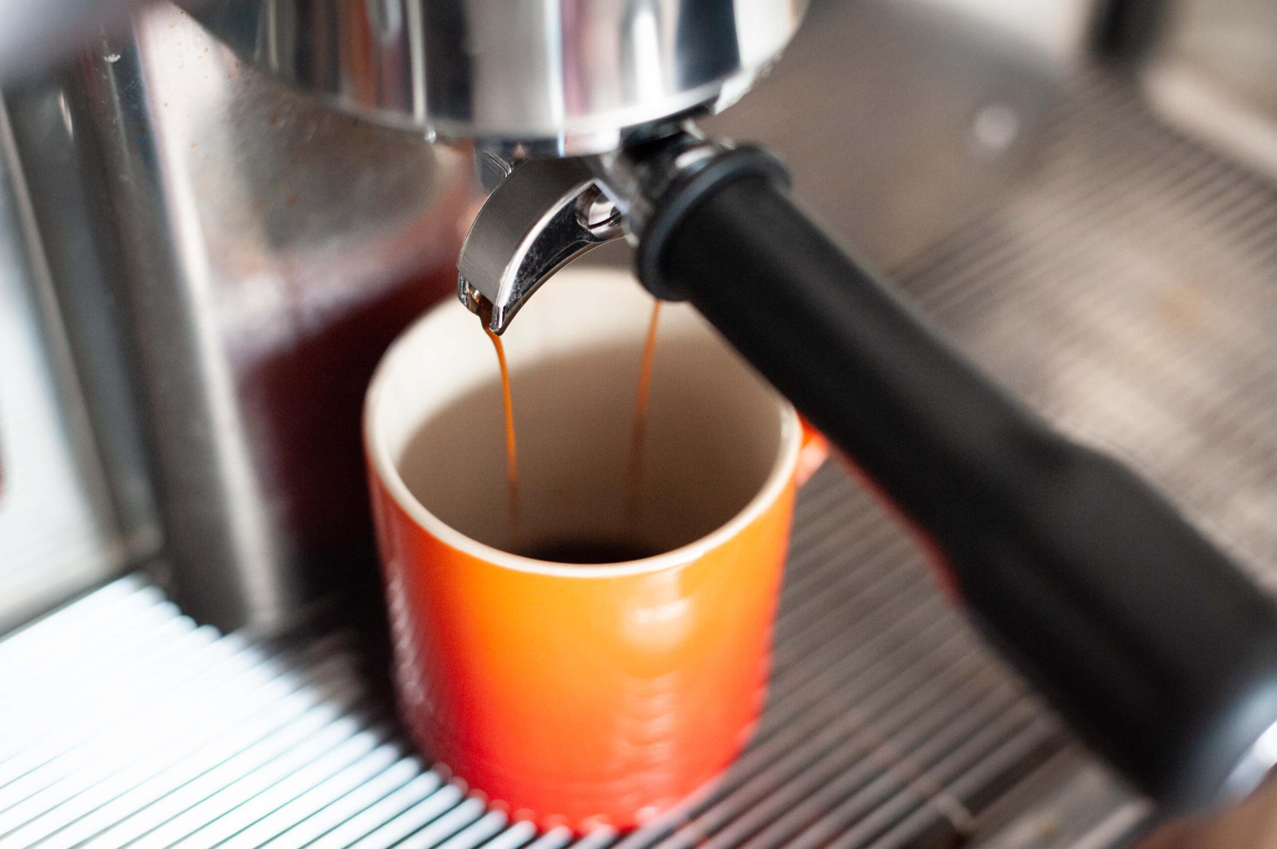 Espresso pouring into orange mug