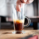 Stirring espresso in latte glass