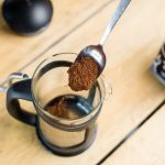 Spooning freshly ground coffee into cafetiere jug