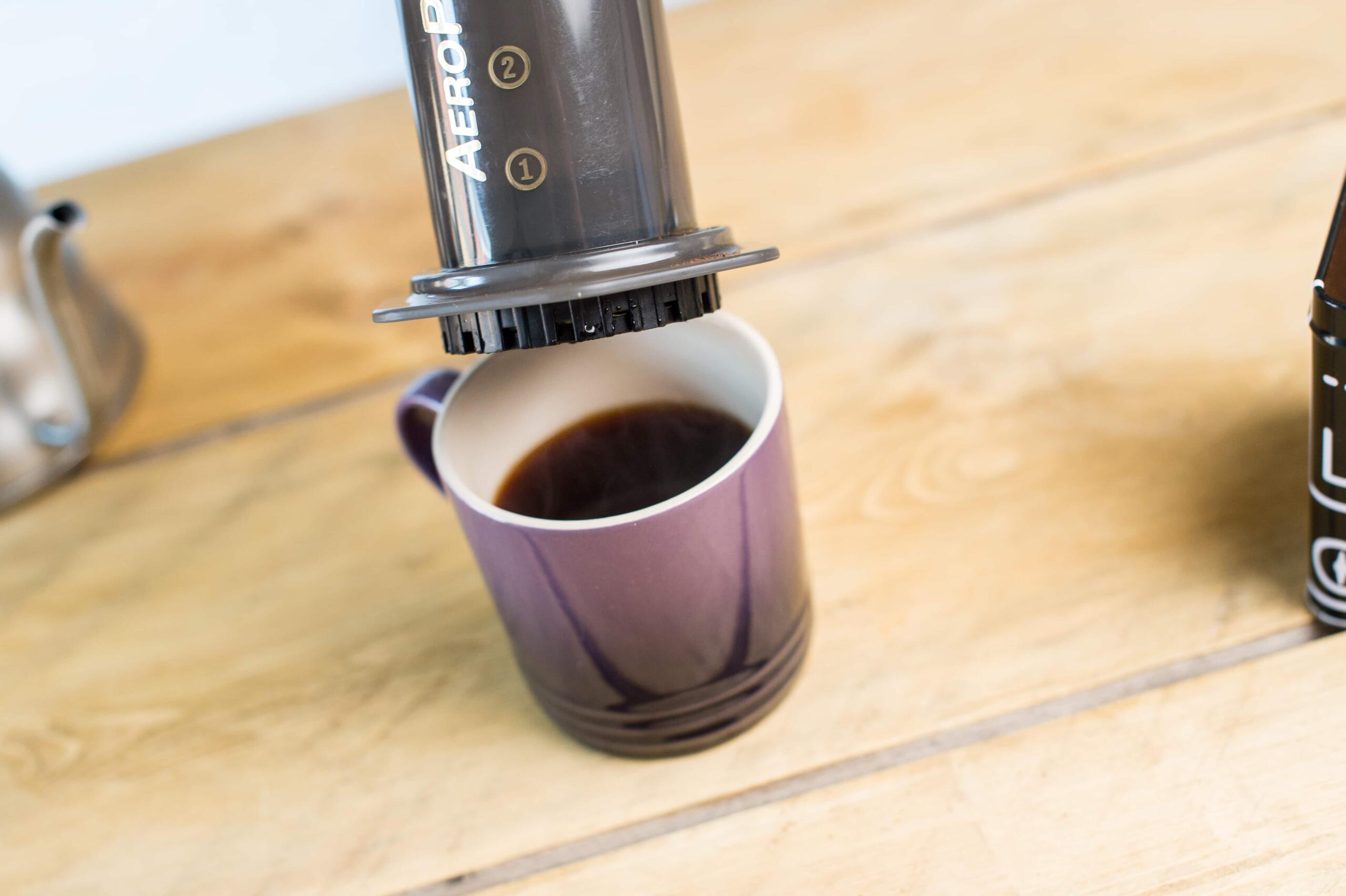 An aeropress being lifted off a purple mug