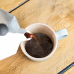 Pouring coffee into a mug from a moka pot