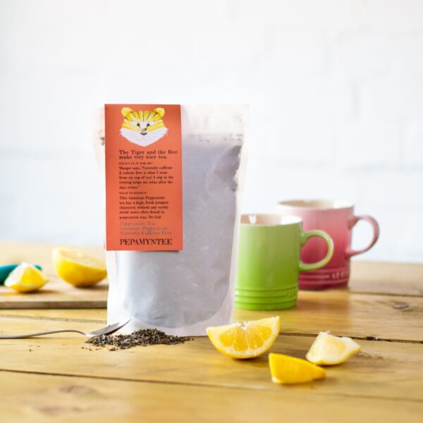 a bag of peppermint tea with cups and a slice of lemon