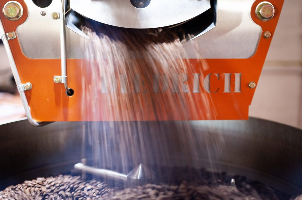 Roasted coffee beans falling into cooling drum