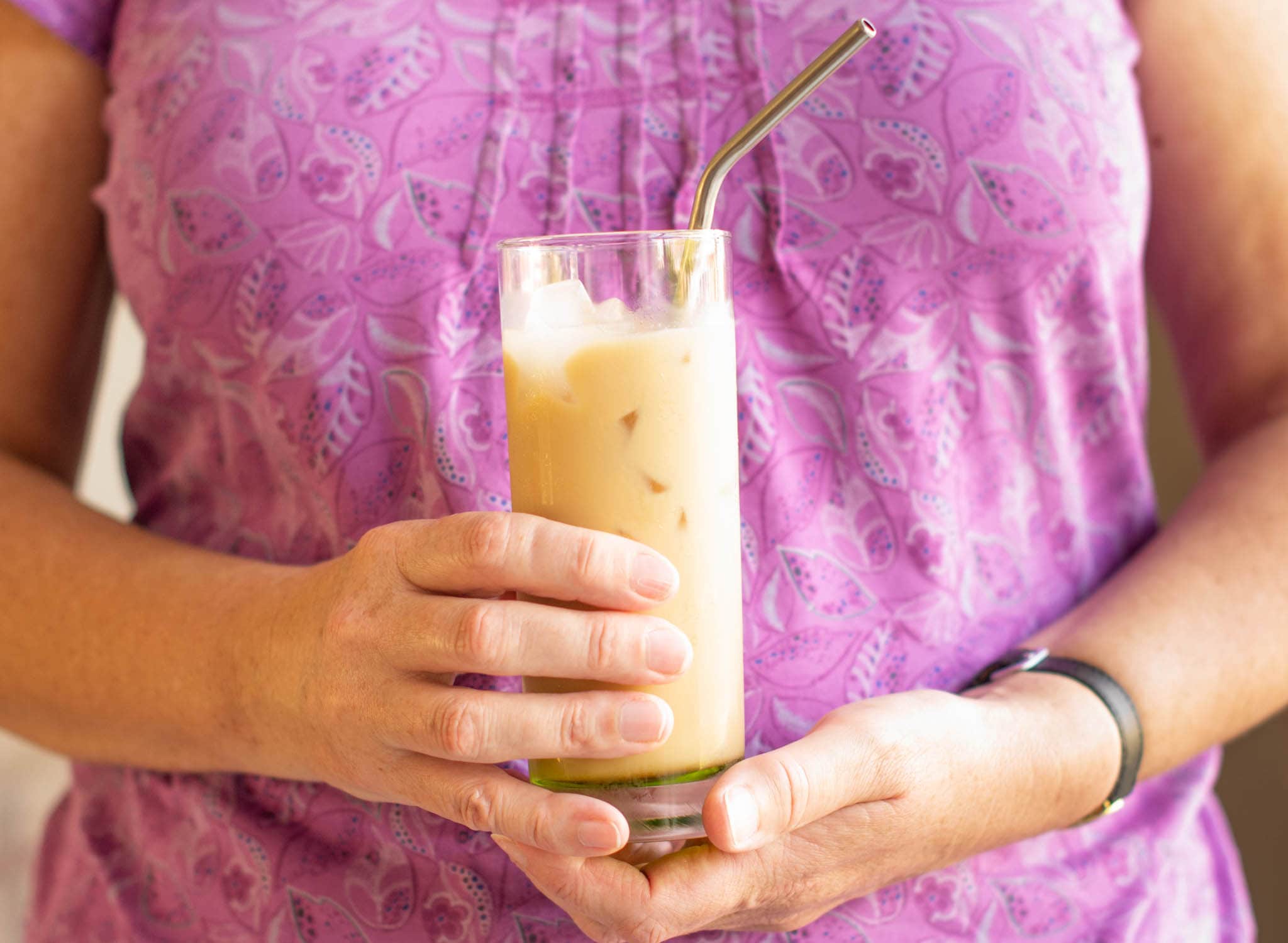 Woman in purple top holding iced latte
