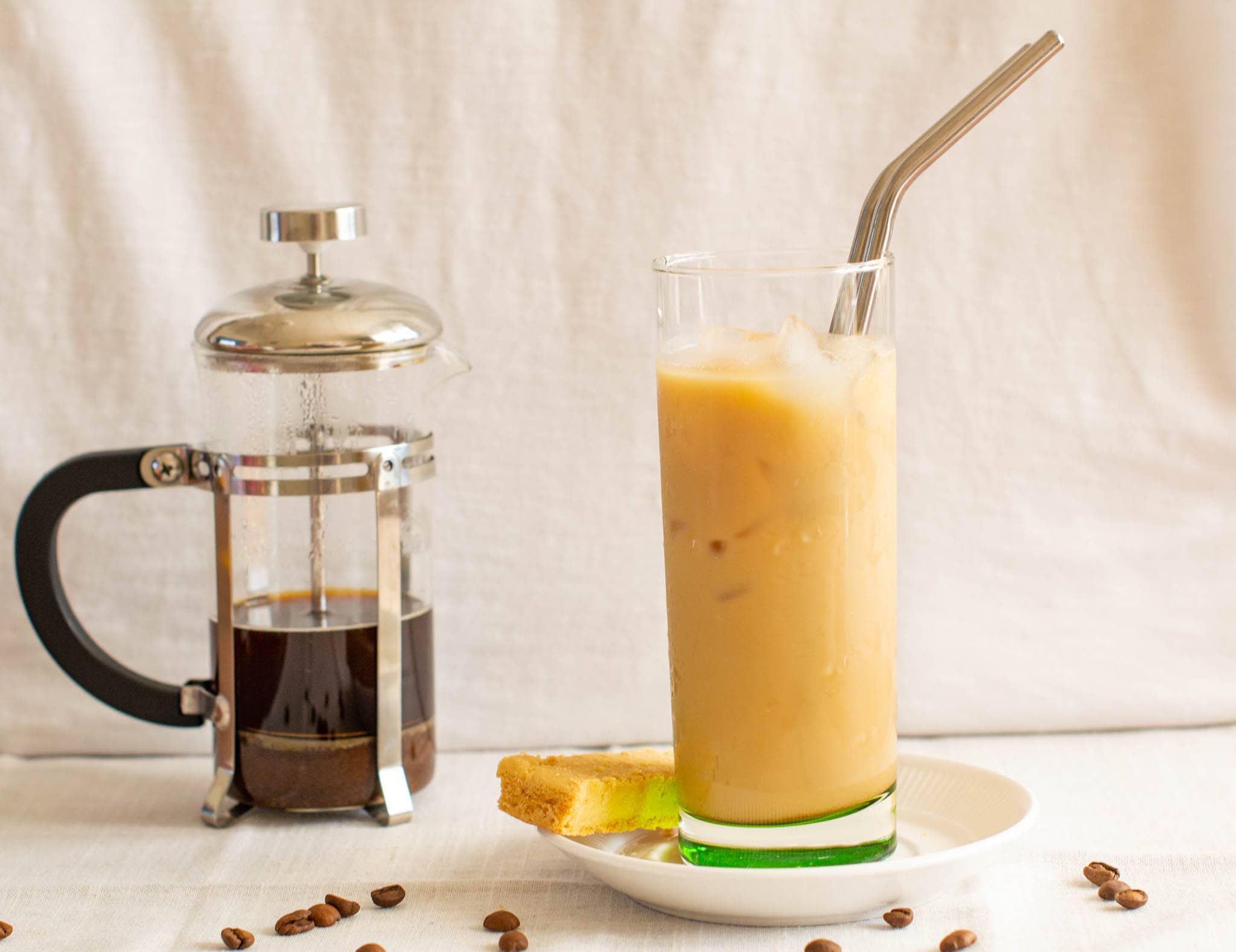 Vanilla iced latte with biscuit beside small cafetiere