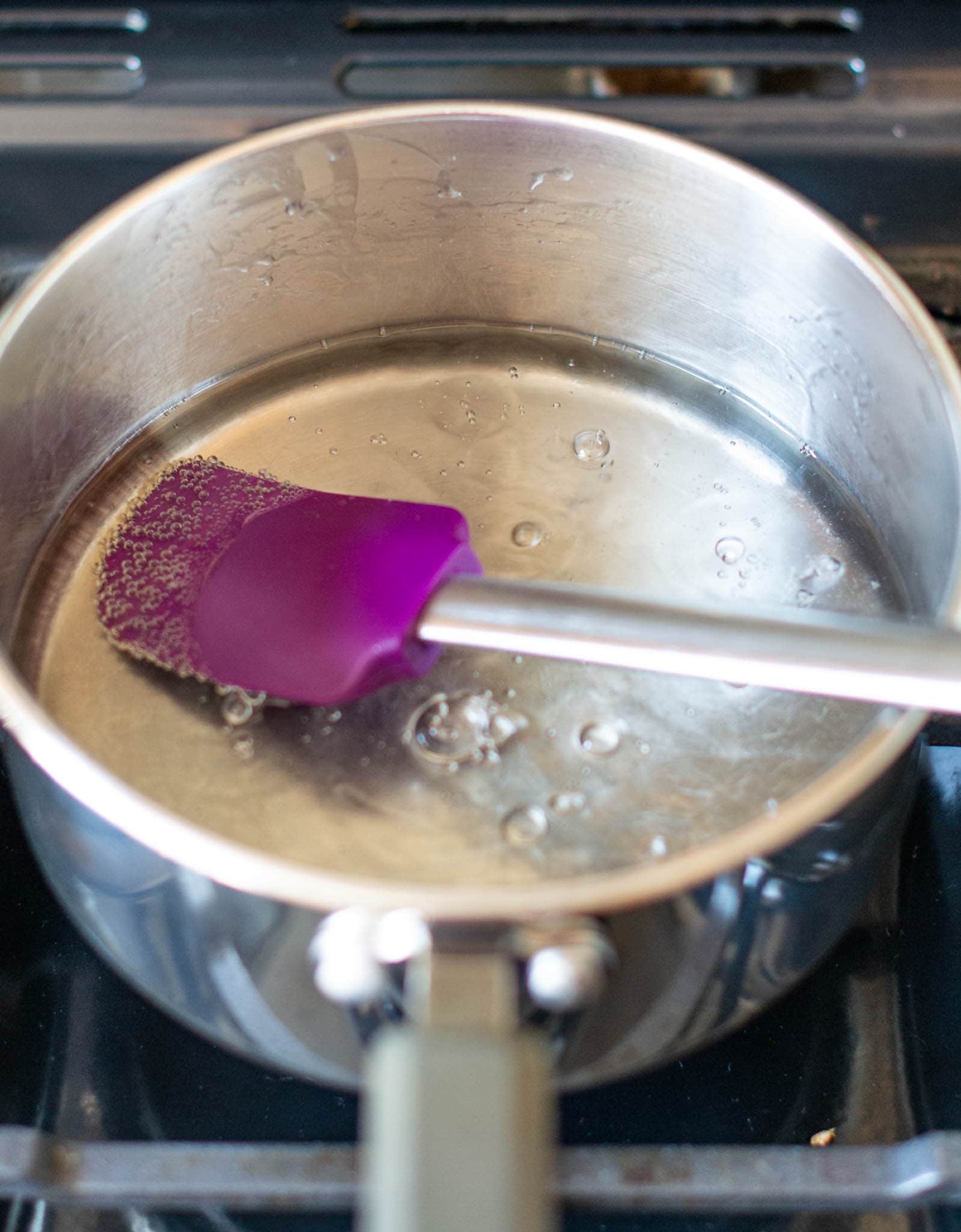 Boiling water and sugar in saucepan with spatula