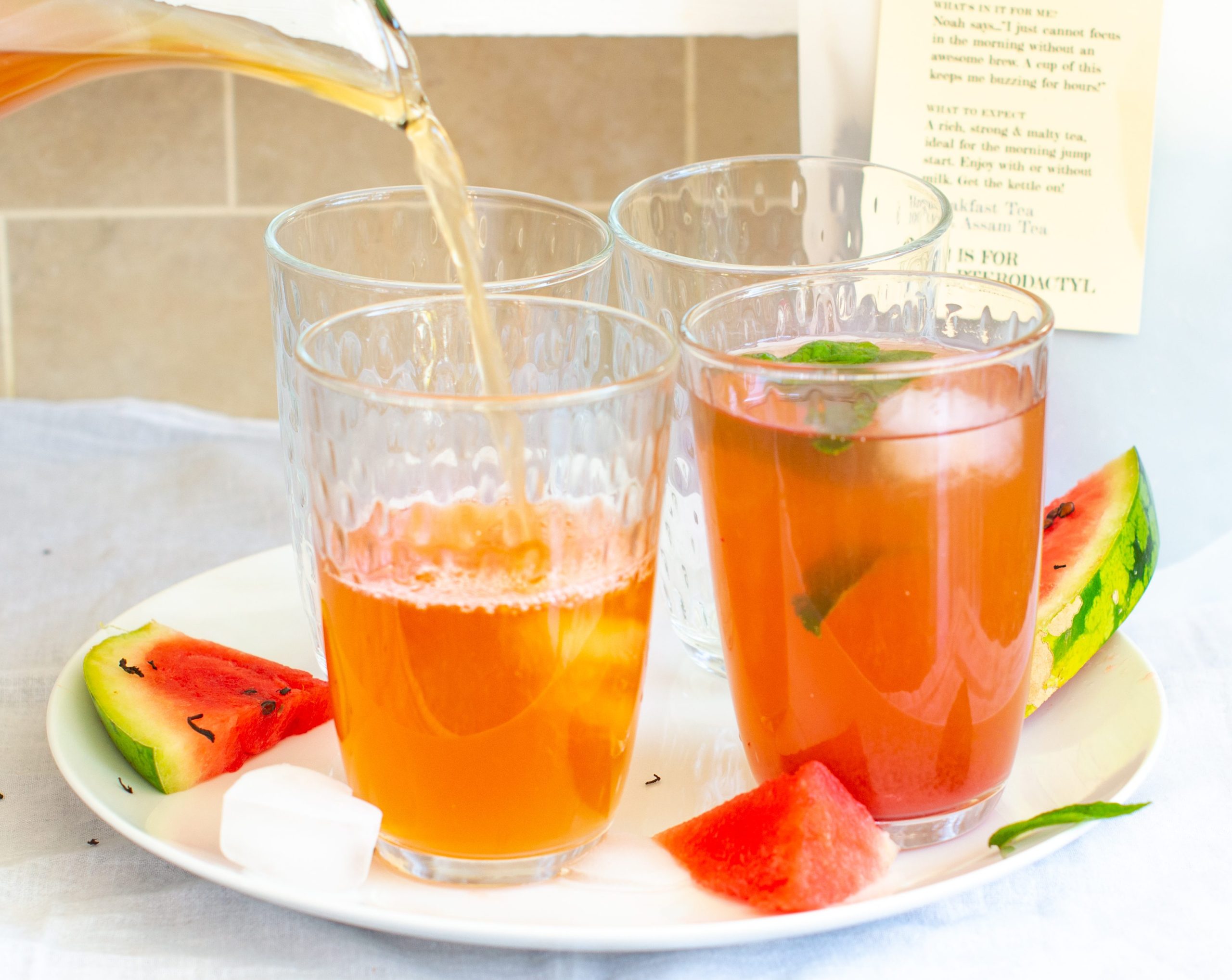 Pouring Watermelon and Mint Iced Tea into glasses sitting on a white plate