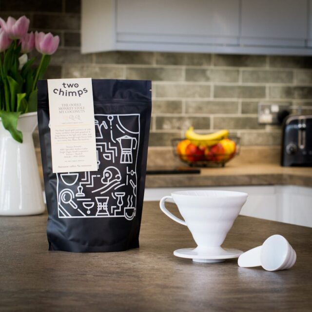 hario v60 coffee dripper with a bag of two chimps coffee and measuring spoon on a kitchen worktop