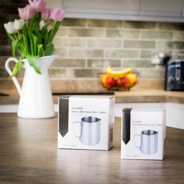 two boxed barista milk steaming jugs in different sizes on a kitchen worktop