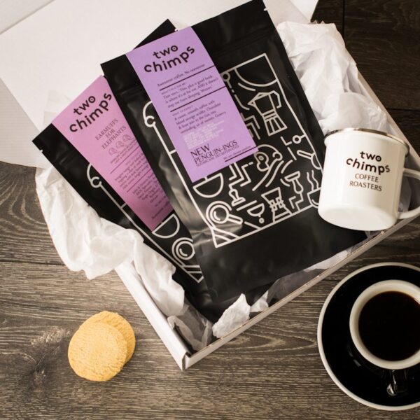 close up of two bags of two chimps coffee and enamel mug in a white gift box