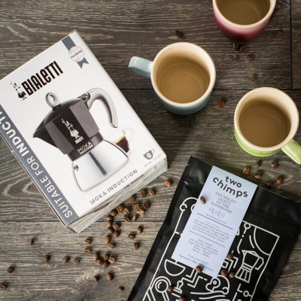 birdseye view of induction moka pot with a bag of two chimps coffee and three mugs