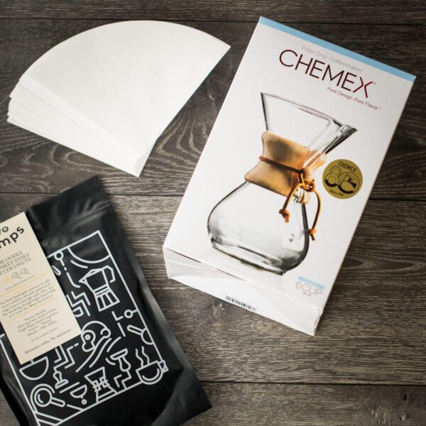 birds eye view of chemex dripper with a bag of two chimps coffee and paper filters on a wooden table
