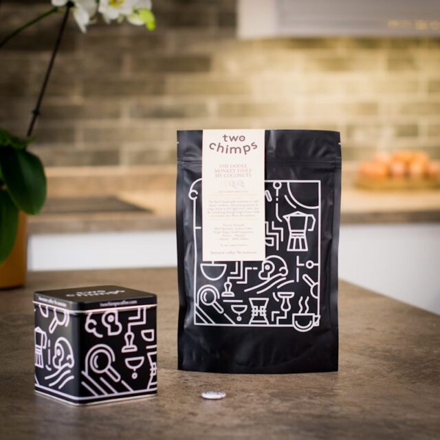 a bag of two chimps coffee with a two chimps tin and magnet on a kitchen worktop