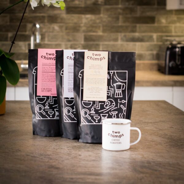 three bags of two chimps coffee with two chimps mug on kitchen worktop