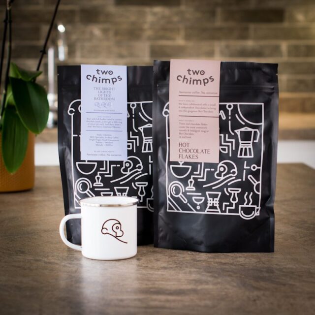 a bag of two chimps coffee with a bag of hot chocolate flakes and mug on a kitchen worktop