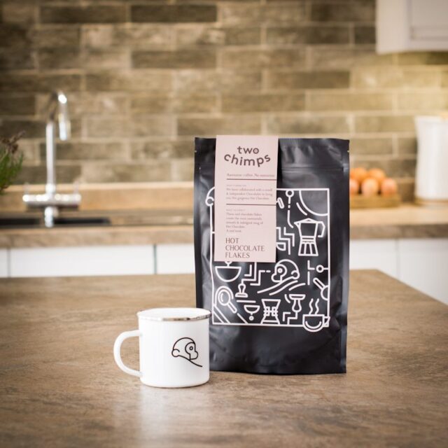 a bag of two chimps hot chocolate flakes with a two chimps enamel mug on a kitchen worktop