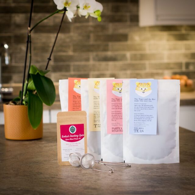 four bags of loose leaf tea with a drinking spice pouch and a tea infuser on a kitchen worktop