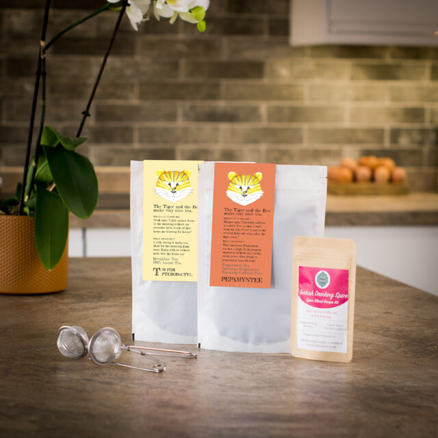 two loose leaf teas with a spice pouch and tea infuser on a kitchen worktop