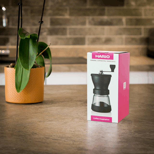 Boxed Hario Ceramic Hand Grinder On Kitchen Worktop available to purchase from the Two Chimps online shop